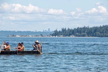 Paddlers on Canoe Journey with the Seattle city line in the distance.