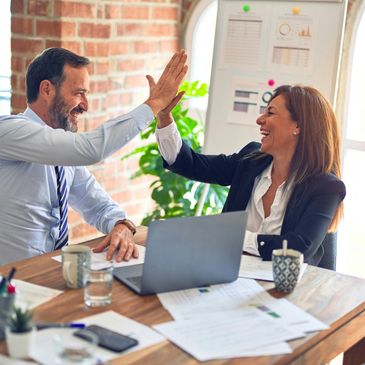 Two colleagues celebrating success with a high-five in the office.