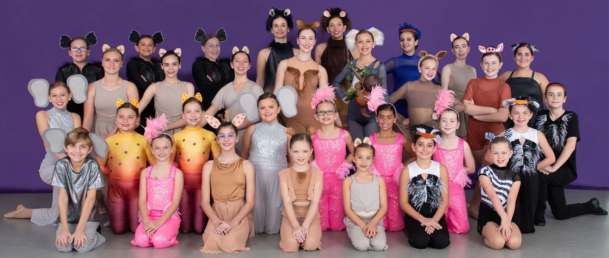 A diverse group of children in colorful animal-themed costumes posing together on a purple background.