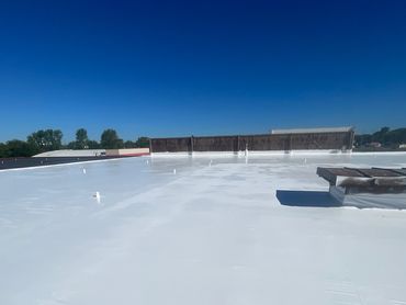 A large, freshly coated white rooftop under a clear blue sky.