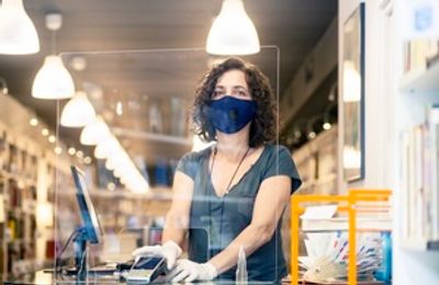 woman behind shop counter face covering gloves
