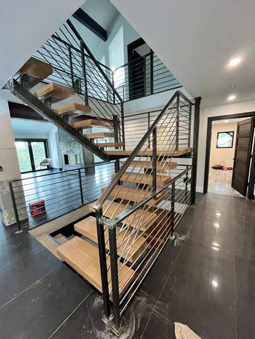 Modern staircase with wooden steps and metal railings in a sleek interior.
