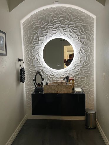 Modern bathroom vanity with illuminated circular mirror and textured wall design.