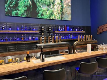 Modern bar with wooden counter and illuminated liquor shelves.