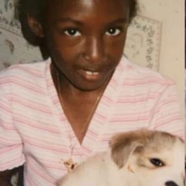 A young person smiles holding a fluffy puppy.
