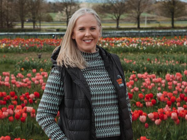 Woman smiling in front of colorful tulips.