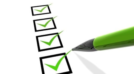 Green pen checking boxes on a checklist.