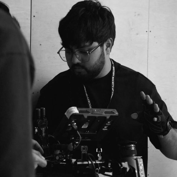 Man wearing glasses filming with a camera.