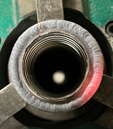 Close-up of a threaded metal pipe with a neatly welded ring.