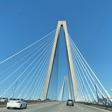 View of Arthur Ravenel Jr. Bridge with cars and clear blue sky.