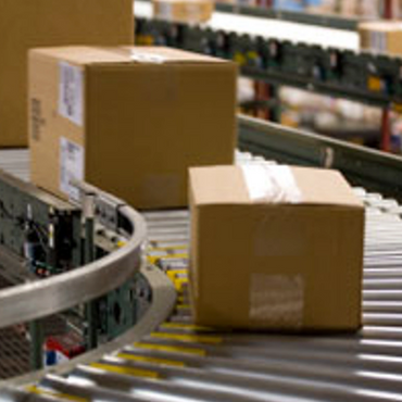 Cardboard boxes moving on a conveyor belt in a warehouse.