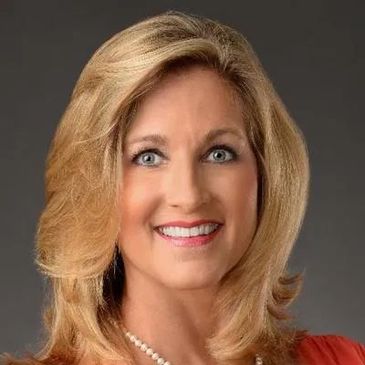 Smiling woman with blonde hair and pearl necklace.
