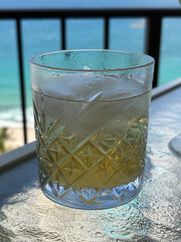 Cocktail glass with ice on table with condensation.