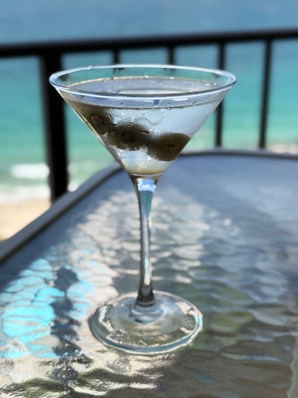 Martini glass with olives with on table with condensation.