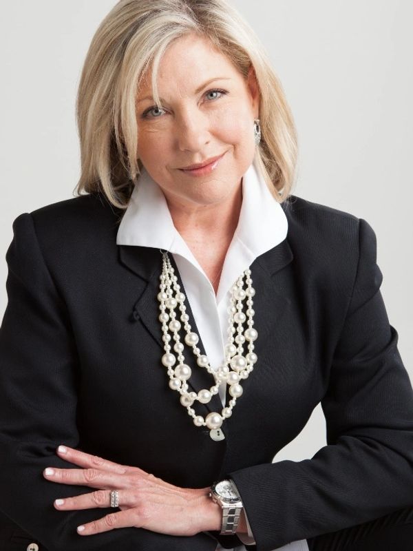 Picture of woman in black coat with white shirt and pearl necklace