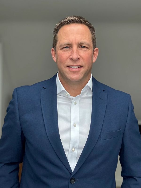 Man in a blue suit and white shirt smiling at the camera.