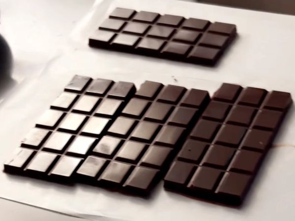 Three dark chocolate bars on a white surface.