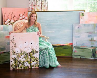 abstract artist sitting with a collection of her art