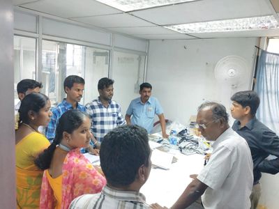 Group of people engaged in a discussion around a table in an office setting.