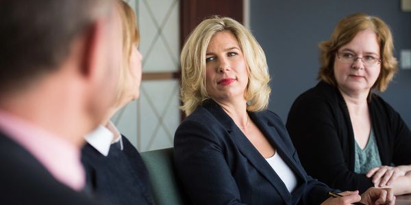 Three professionals engaged in a serious discussion in a meeting room.