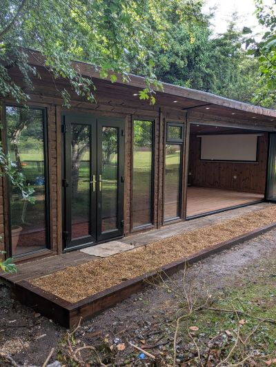 Modern wooden outdoor structure with large glass doors and an open side.