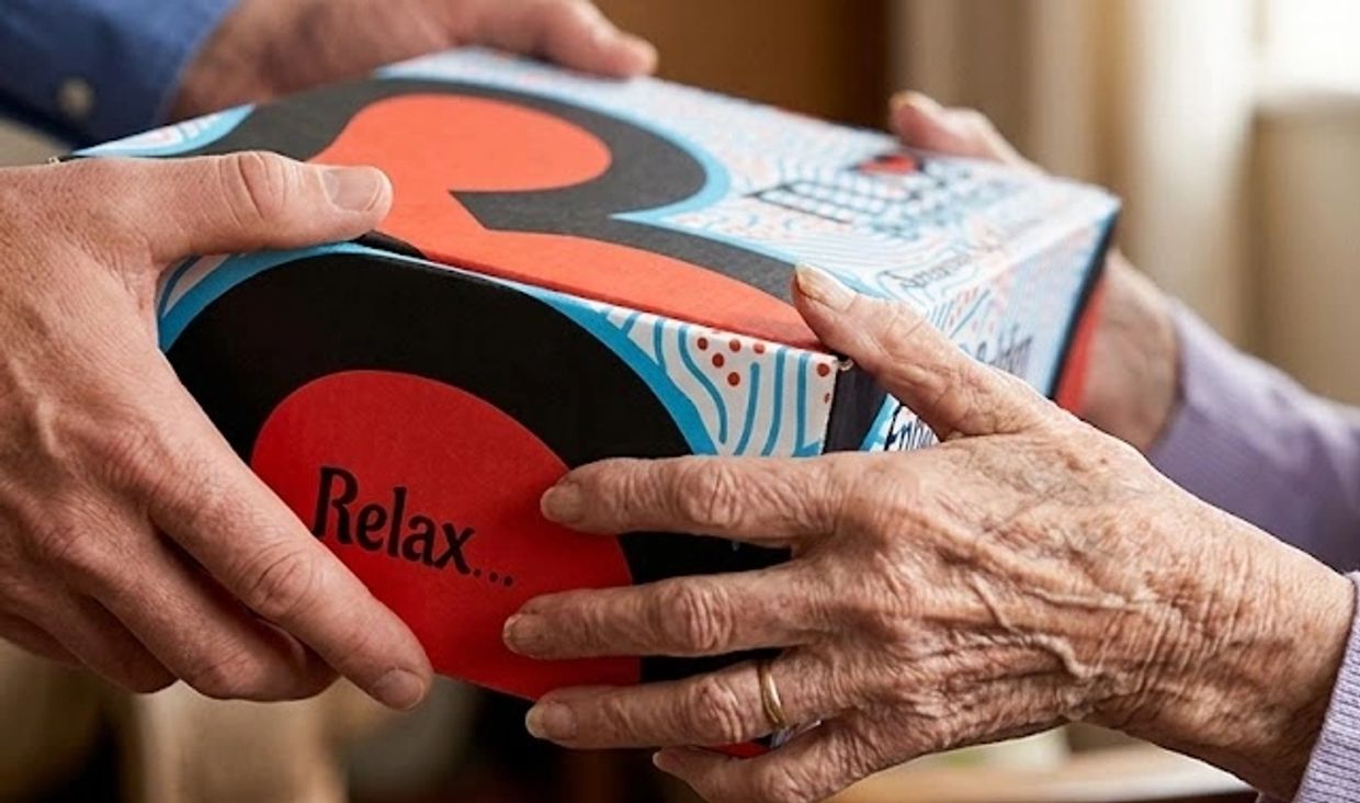 Hands of two people exchanging a colorful box with 'Relax' on it.
