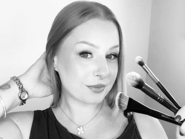 Woman holding makeup brushes and posing.
