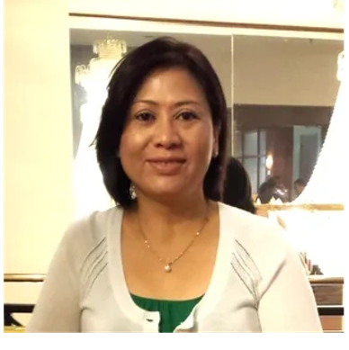 A woman with short dark hair smiling indoors.