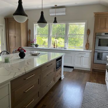 Bright modern kitchen renovation in Newport, RI featuring white custom cabinetry, large center islan