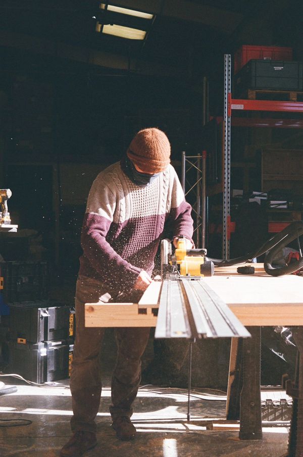 Person using a power tool to cut wood in a workshop.