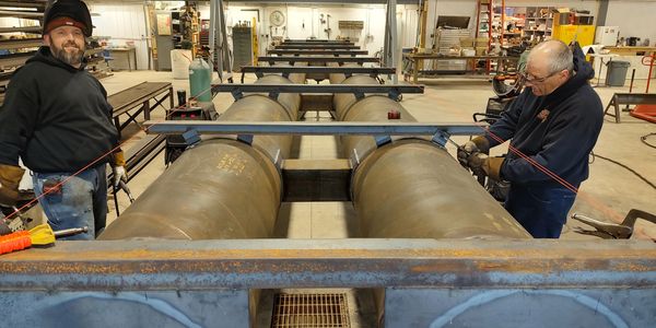 two men working on pipes for a push boat