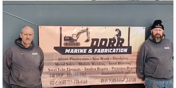 Two men standing in front of the Dorr Marine banner