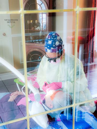 Mobile dental hygienist Monica Cordova working on man's teeth at home, view through glass door