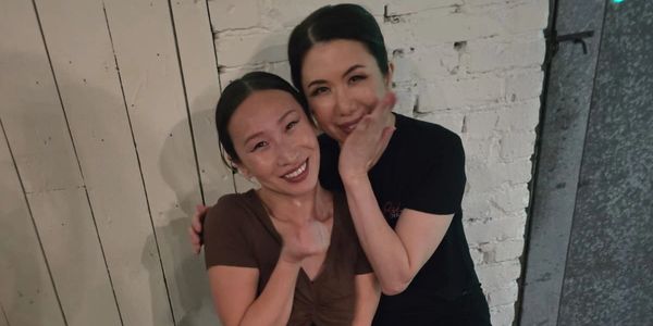 Two women smiling and posing closely together indoors.