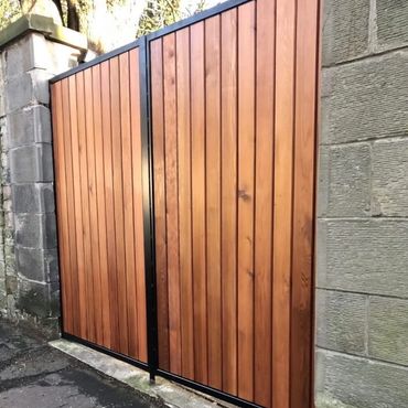Wooden gate with black metal frame between stone walls.