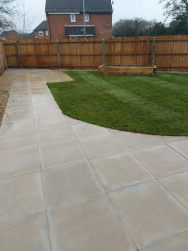 Backyard with grass, stone path, and wooden fence.