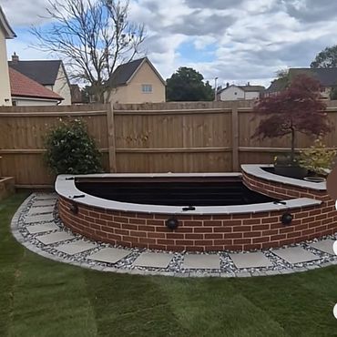 Backyard fish pond with brick edging and stepping stones.