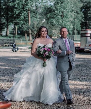 Father of the bride and bride walk toward guests