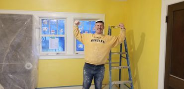 Man posing in a newly painted yellow room.