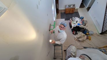 Person painting a wall while smiling at the camera.