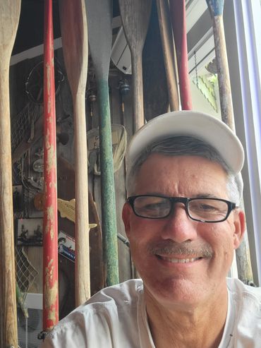 Man smiling with paddles in the background.