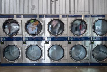 Row of Dexter stack dryers in a laundromat with some running and some empty.