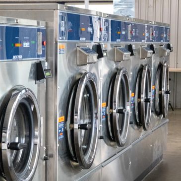 Row of industrial washing machines in a laundromat.
