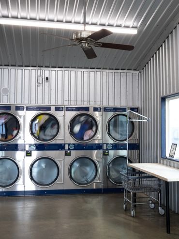 Interior of a modern laundromat with dryers and folding table.