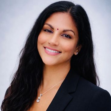 Smiling woman with long black hair and a bindi.