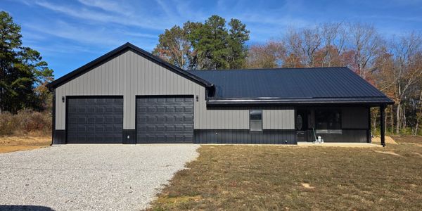 Modern single-story house with two-car garage and dark metal roof.