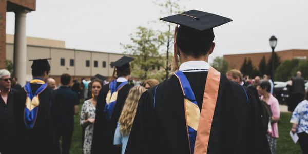 Graduates in caps and gowns at an outdoor ceremony.