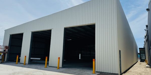 Large modern warehouse with open bays and yellow bollards.