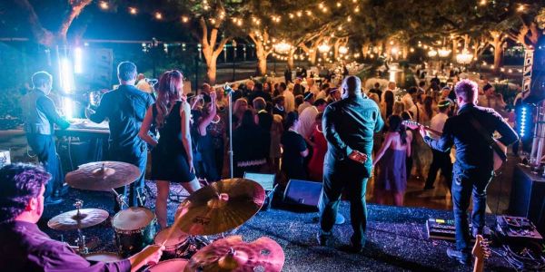 A lively outdoor concert with a band performing for a dancing crowd under string lights.