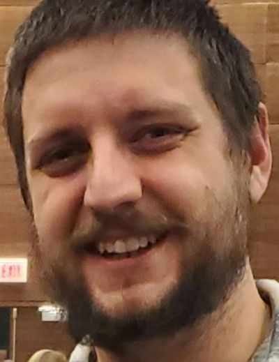 Close-up of a smiling bearded man indoors.
